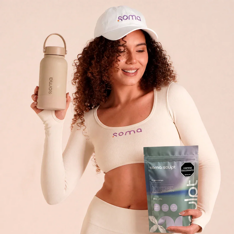Mujer con ropa deportiva sosteniendo botella y suplemento Soma Sculpt, ideal para rutinas de fitness y bienestar.