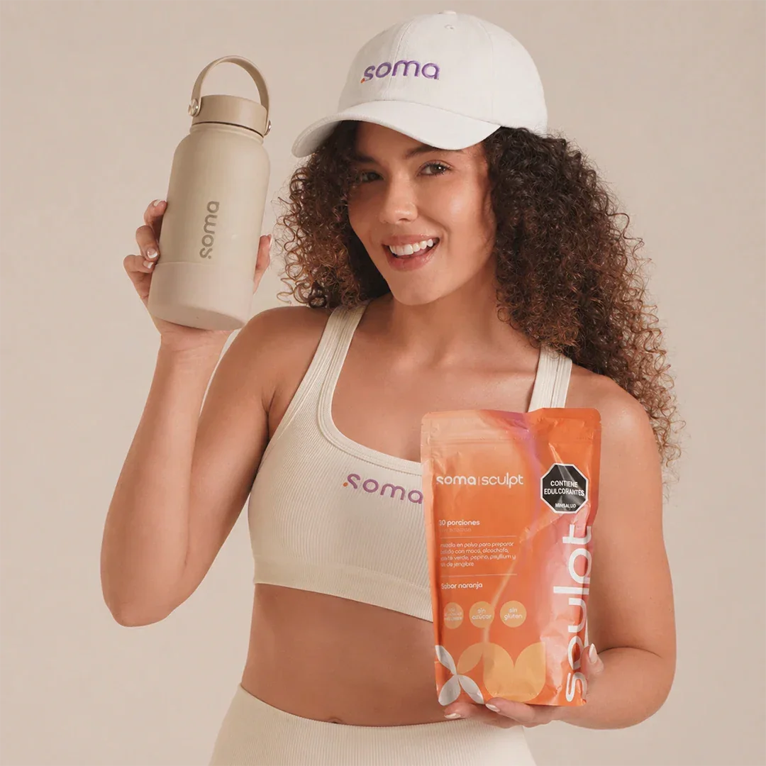 Mujer con gorra y top Soma sosteniendo botella y paquete Soma Sculpt sabor naranja para batidos saludables