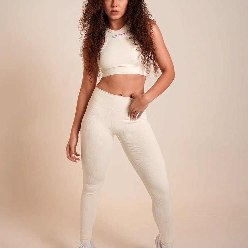 Conjunto deportivo blanco ribeteado con top y leggings de cintura alta, ideal para yoga y entrenamiento.
