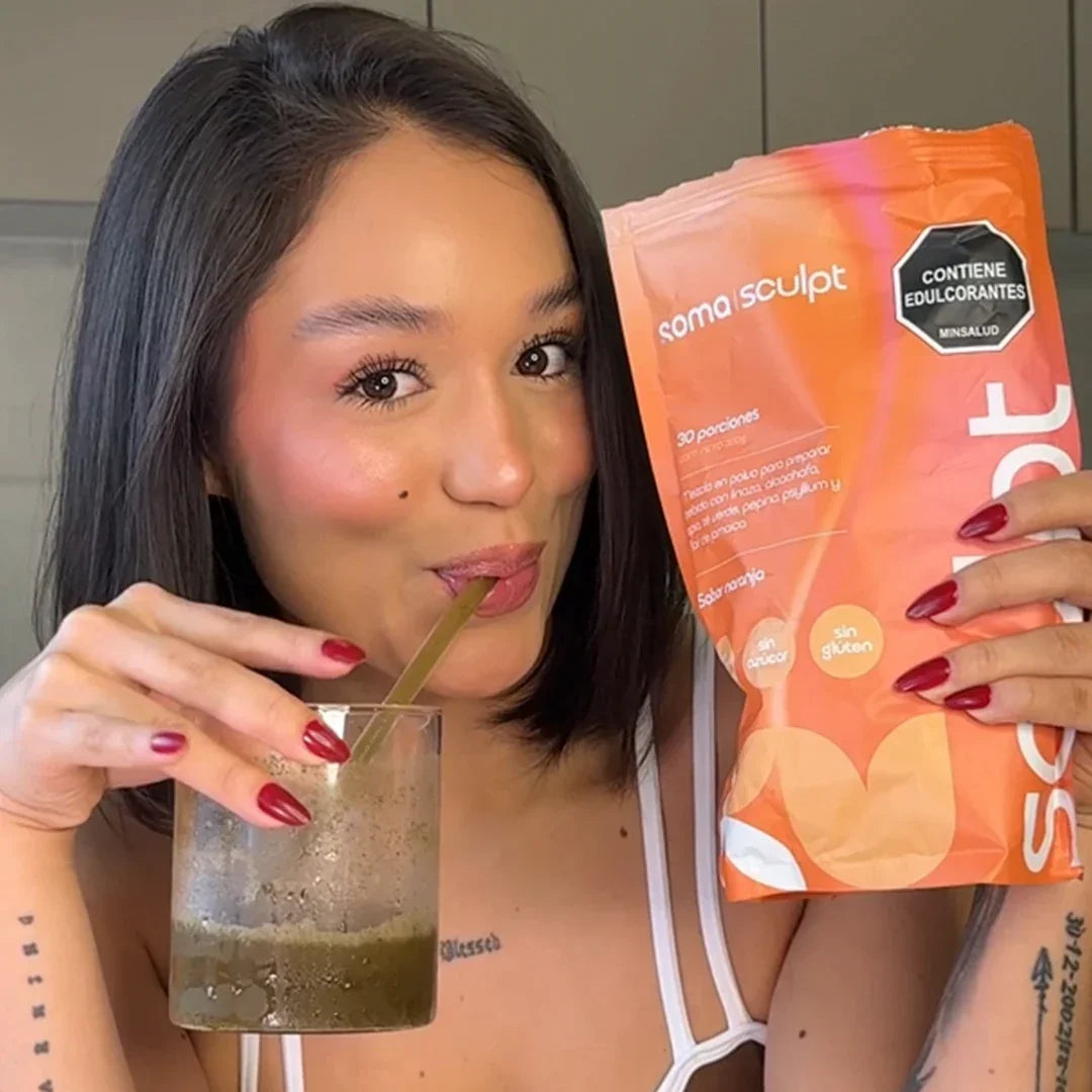 Mujer tomando SOMA Sculpt sabor naranja con pajita, sosteniendo bolsa de 30 porciones sin azúcar ni gluten, ideal para bienestar digestivo y saciedad diaria