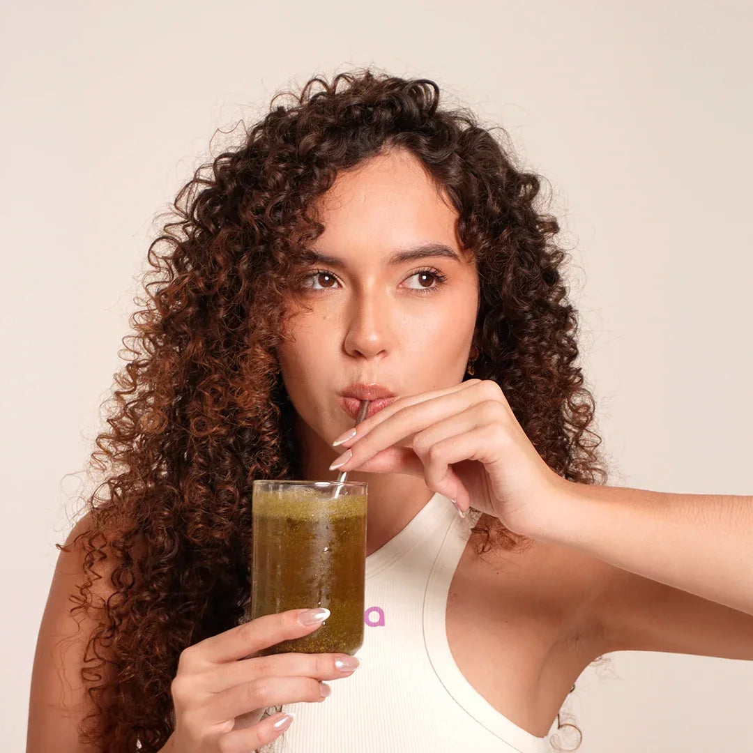 Mujer tomando SOMA Sculpt de piña con pajita, bebida funcional para saciedad y bienestar digestivo en rutina diaria
